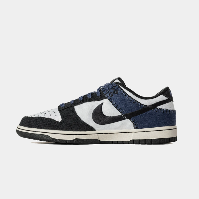 Nike Dunk Low Retro sneakers in black, white, and navy blue featuring textured suede overlays, contrast stitching, and black rubber sole, side view.