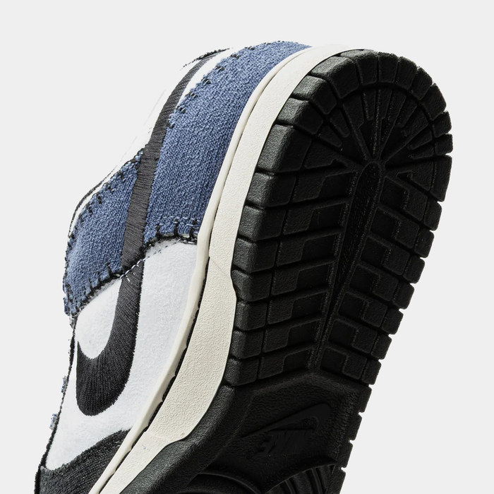 Nike Dunk Low Retro sneakers close-up of outsole and textured upper featuring denim blue overlays, black accents, and rubber black sole.