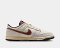 Nike Dunk Low sneakers in cream and burgundy with leather upper, perforated toe box, and contrasting sole, side view.