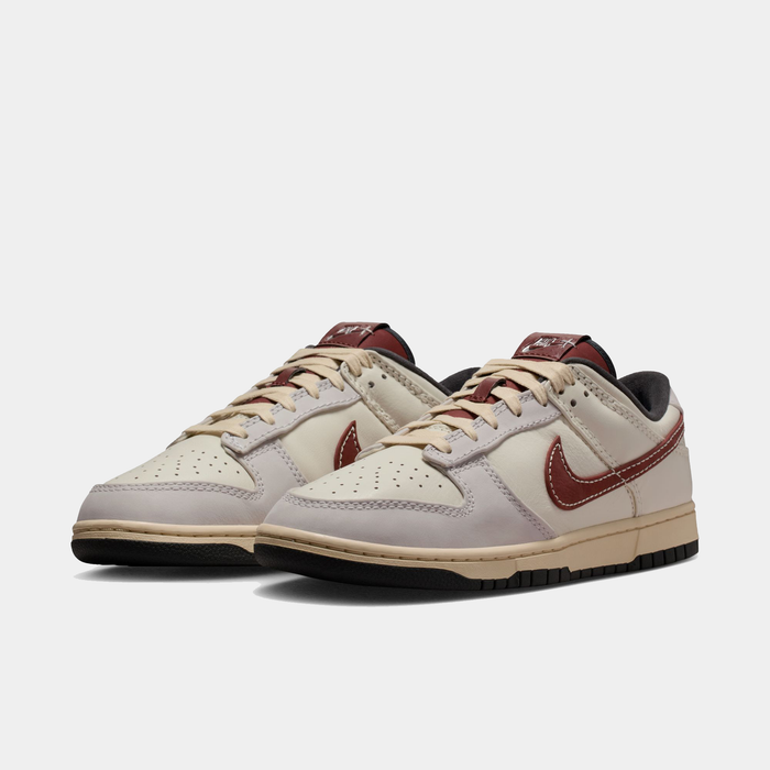 Nike Dunk Low sneakers in off-white and maroon with leather upper and perforated toe box, front angle view.