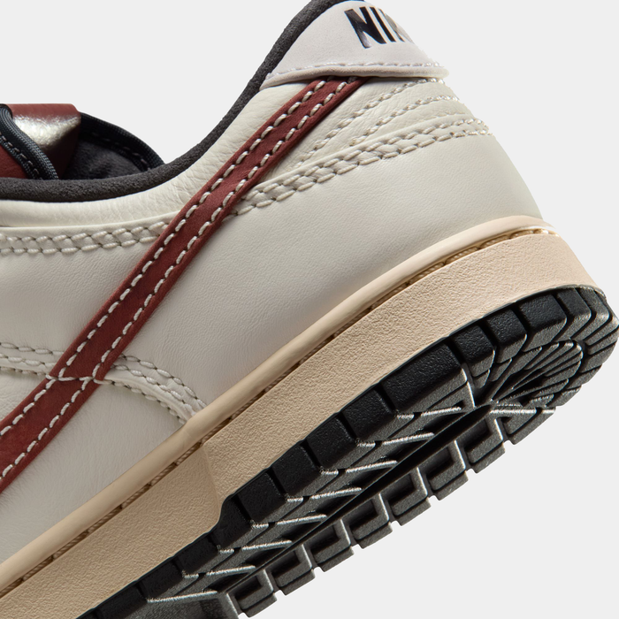 Nike Dunk Low sneakers in cream with burgundy accents, detailed stitching, and black outsole, back and sole close-up view.