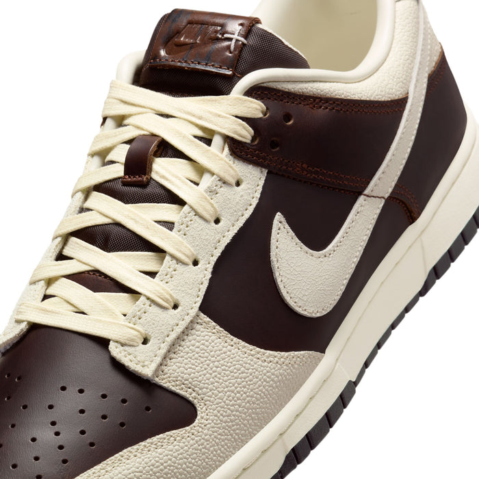 Nike Dunk Low sneakers in brown and cream with a leather upper, textured overlays, and contrasting cream laces, angled close-up view.