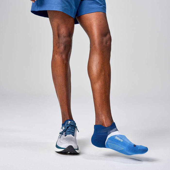 Feetures Elite Light Cushion No Show Tab socks in blue with arch support detail, worn by runner.
