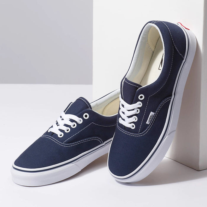 Vans Era Core sneakers in navy blue canvas with white stitching, white laces, and waffle rubber outsole, angled side view.