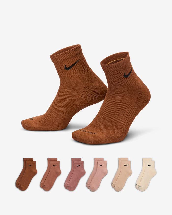 Nike Everyday Plus Cushioned Ankle Socks in assorted brown, pink, and beige tones with ribbed cuffs and black Swoosh logo, front view.