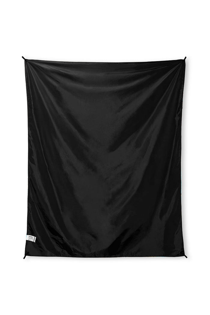 Nomadix Festival Blanket in solid black, lightweight and durable material with corner attachment loops, front view.