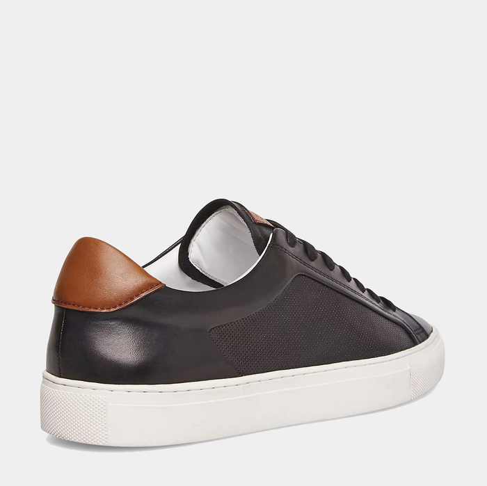 Steve Madden Finneas sneakers in black leather with textured side panel, brown heel accent, and white rubber sole, back view.