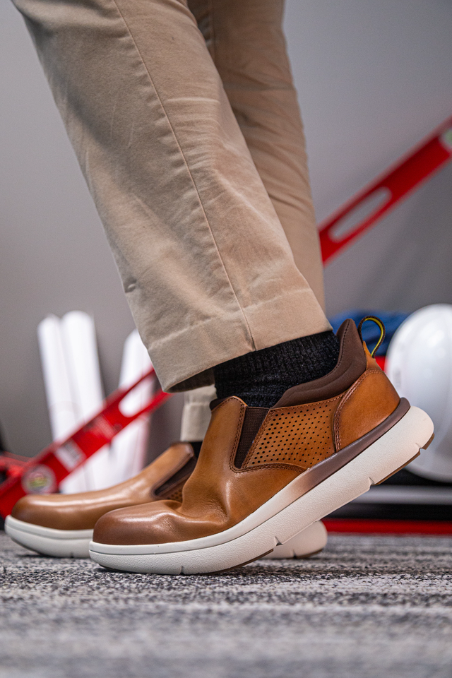 Florsheim Work Fleet Work Comp Toe Slip On shoes in tan leather with perforated side panels and slip-on design, lifestyle context.