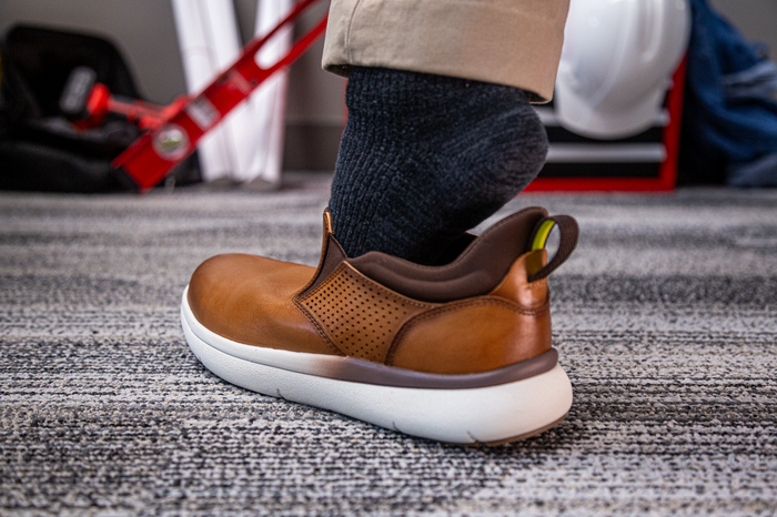 Florsheim Work Fleet Work Comp Toe Slip On shoes in brown leather with perforated details and white cushioned outsole, side view worn.
