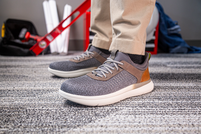Florsheim Work Fleet Work Comp Toe Sneaker in gray with textured upper, tan leather accents, cushioned sole, worn by person indoors.