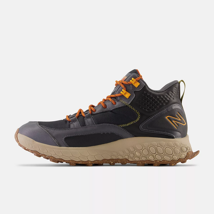 New Balance Foam X Hierro Mid GTX hiking shoes in dark gray with orange laces, Gore-Tex upper, and rugged beige outsole, side view.