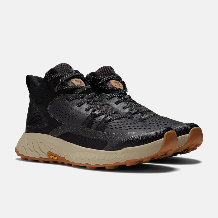 New Balance Foam X Hierro Mid GTX hiking boots in black with Gore-Tex uppers, beige foam midsoles, and Vibram outsoles, angled front view.