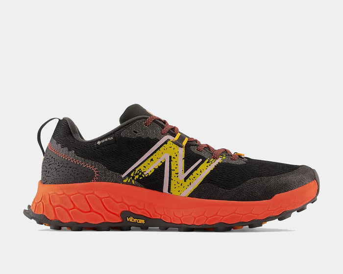 New Balance Fresh Foam Hierro v7 trail running shoes, black mesh upper with yellow accents and Vibram orange outsole, side view.