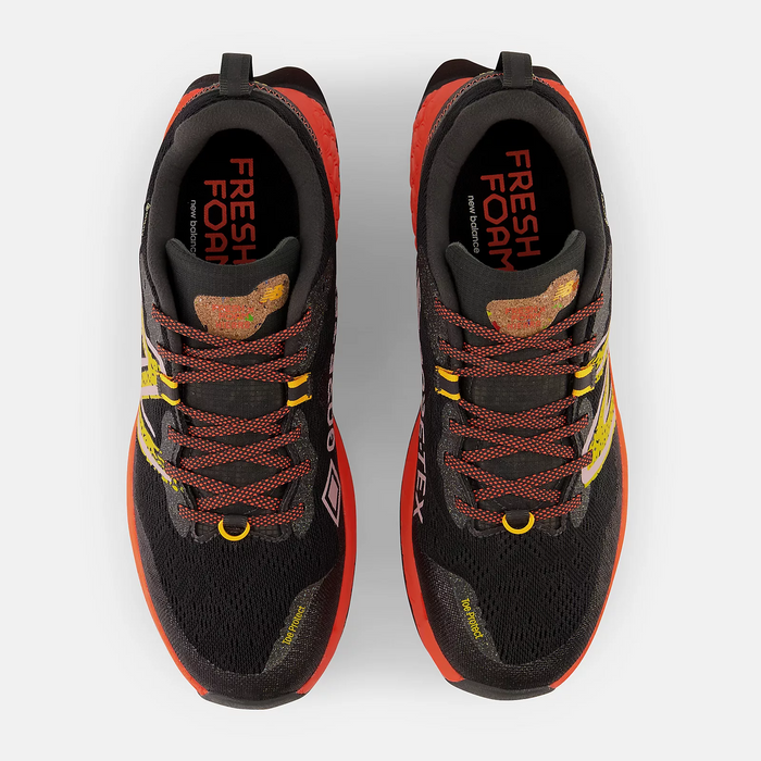 New Balance Fresh Foam Hierro v7 trail running shoes top view showcasing black mesh upper, red accents, orange sole, and rugged lace design.