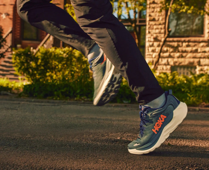 HOKA Gaviota 6 running shoes in blue with orange logo, cushioned midsole, and durable outsole, worn by a runner on pavement.