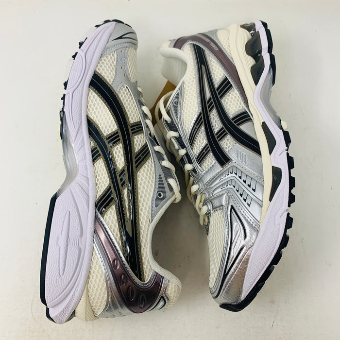 Brand new ASICS Gel-Kayano 14 Cream Black Metallic Plum sneakers rest elegantly on a pristine brown ASICS shoe box. With a mesh upper, metallic accents, and black details, these shoes stand out against a neutral backdrop.
