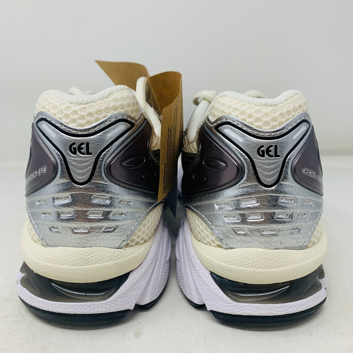 Brand new ASICS Gel-Kayano 14 Cream Black Metallic Plum sneakers rest elegantly on a pristine brown ASICS shoe box. With a mesh upper, metallic accents, and black details, these shoes stand out against a neutral backdrop.