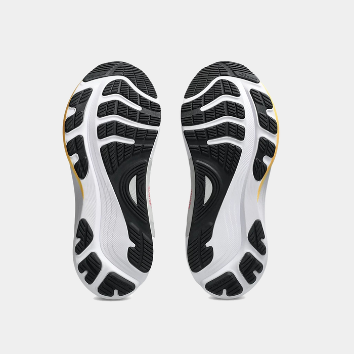Asics Gel-Kayano 32 running shoe soles showing black rubber tread pattern and white midsole with yellow accents, bottom view.
