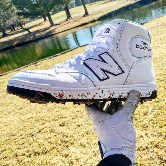 Golfkicks GOLFKICKS® V5 Traction Kit on white shoe, outdoor setting with golfer holding shoe.