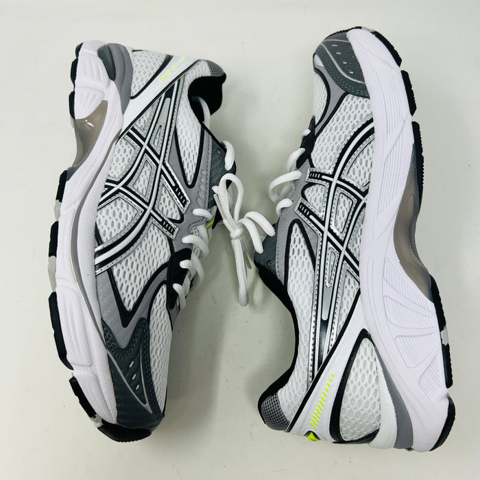 A brand new pair of ASICS GT-2160 JJJJound White sneakers, featuring mesh details and black stripes, is displayed on a black ASICS shoe box with extra laces in front for a complete authentic look.