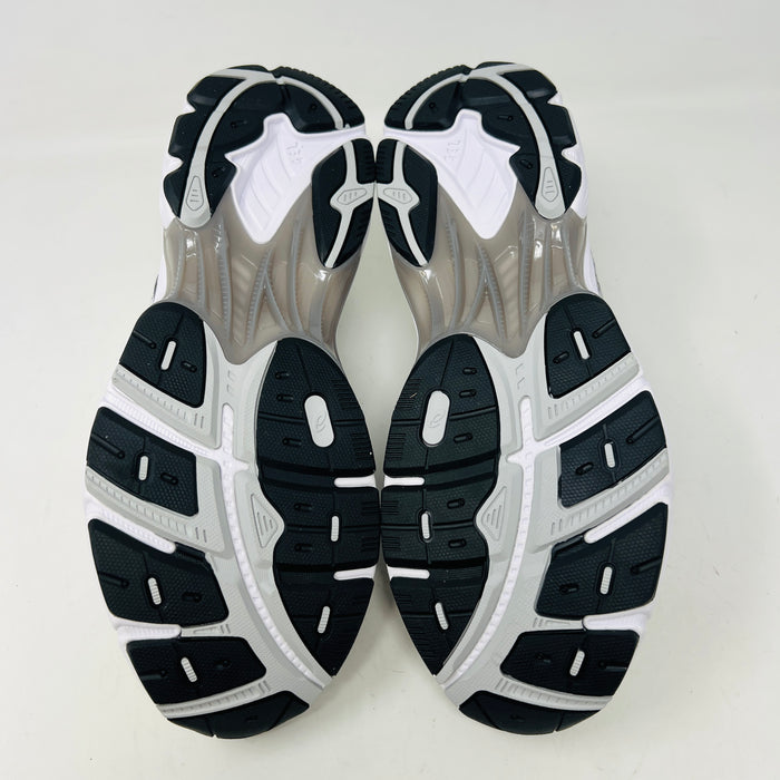 A brand new pair of ASICS GT-2160 JJJJound White sneakers, featuring mesh details and black stripes, is displayed on a black ASICS shoe box with extra laces in front for a complete authentic look.