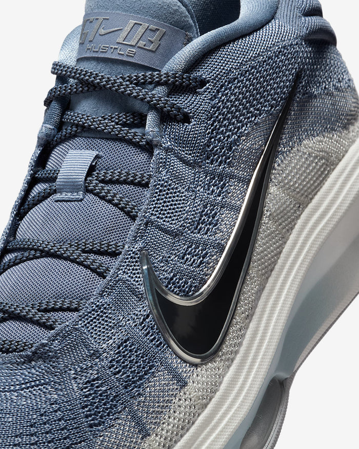 Nike G.T. Hustle 3 basketball shoes in textured blue and gray knit upper with black Nike Swoosh logo and durable sole, close-up side view.