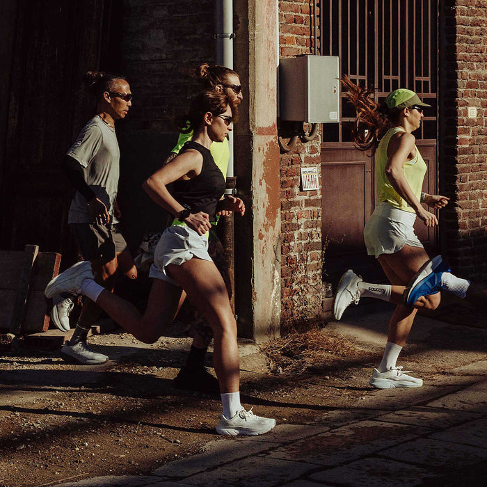 "Saucony Guide 18 running shoes in white with support features and breathable mesh upper, worn by runners outdoors."