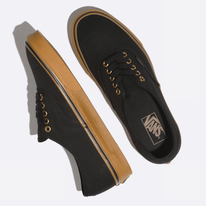 Vans Gum Authentic sneakers in black canvas with gum brown rubber outsole and gold-tone eyelets, top and side views.