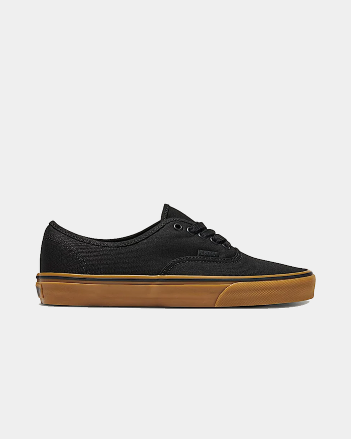 Vans Gum Authentic sneakers in black canvas upper with gum rubber outsole, side view showing lace-up design and minimalist branding.
