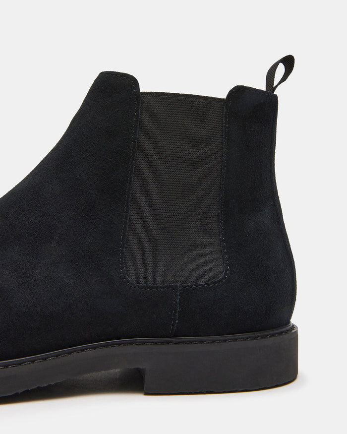 Steve Madden Highline Chelsea Boot in black suede with elastic side panel and pull tab, side view close-up.