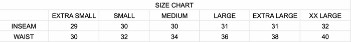 The Holy Ground Cargo Black pants, featuring large side pockets and a subtle shine, are on a wooden floor. Available in XS-XXL with a white logo on one pocket and a visible waist tag. Be sure to consult the size chart for the perfect fit.