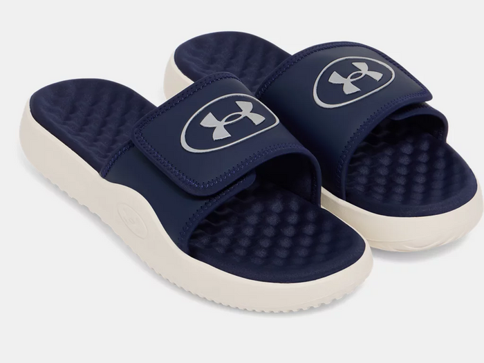 Under Armour Ignite Pro 8 Slides in navy blue with cushioned footbed and adjustable strap featuring logo details, angled front view.
