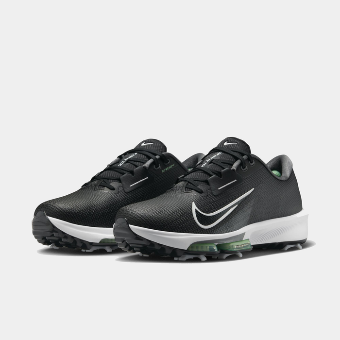 Nike Infinity Tour 2 golf shoes in black with white Swoosh logo, textured upper, green accents, and spiked sole, angled front view.