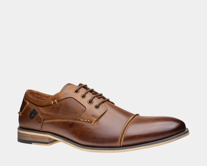 Steve Madden Jagwar dress shoes in brown leather with perforated side panel, cap toe detailing, and layered heel, side view.