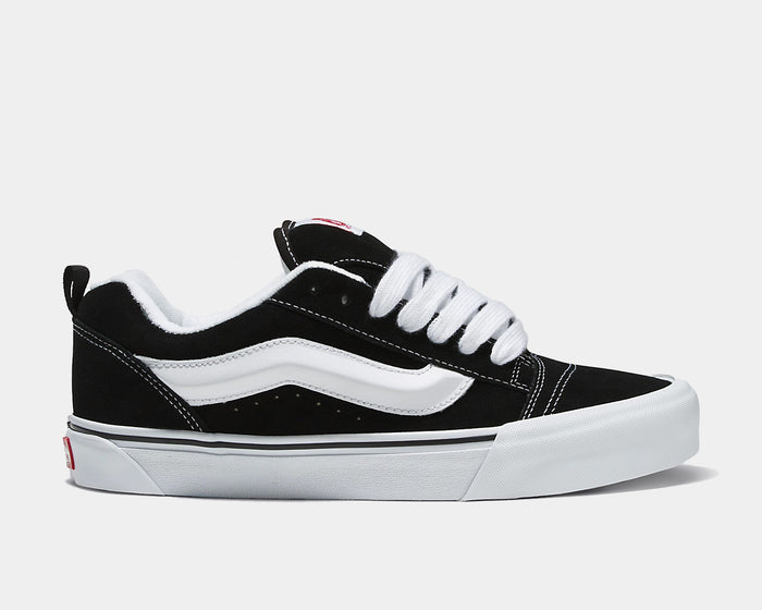 Vans Knu Skool Core sneakers in black suede with white side stripe, thick white laces, and vulcanized outsole, side view.