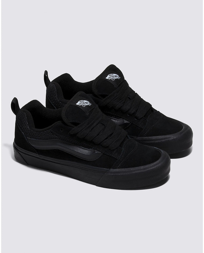 Vans Knu Skool Core sneakers in all-black with suede upper, padded tongue, and signature sidestripe, angled side view.