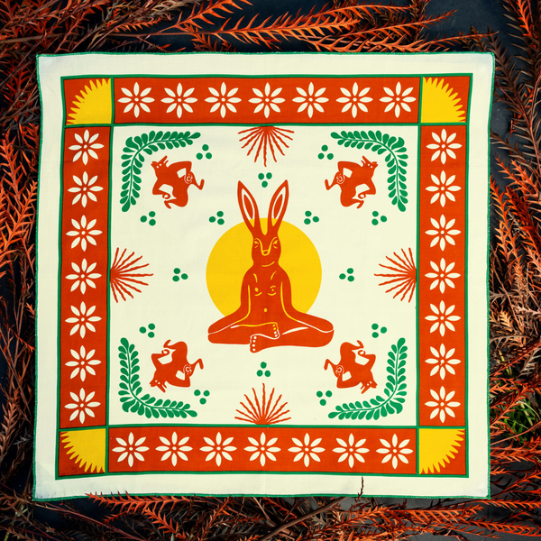 Bandits "La Magia De Tochtli" bandana featuring vibrant orange, yellow, green, and white rabbit-themed design with floral and geometric accents, flat lay view.
