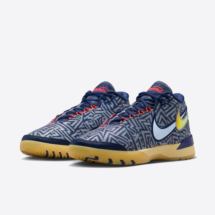 Nike LeBron NXXT Genisus basketball shoes featuring blue geometric-patterned upper, orange accents on the laces, yellow outsole, and multi-tone Nike swoosh, front-side angle.