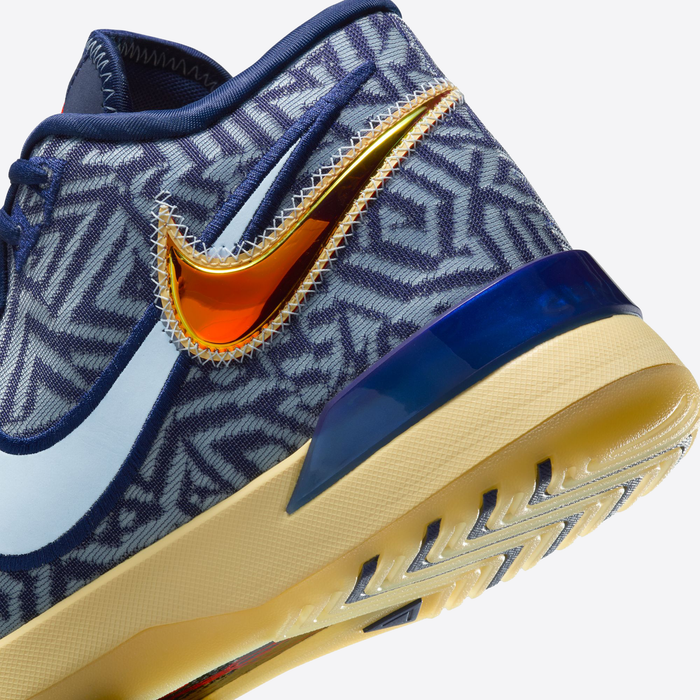 Nike LeBron NXXT Genisus basketball shoes with geometric blue patterned upper, metallic orange Swoosh, and beige outsole, side angle.