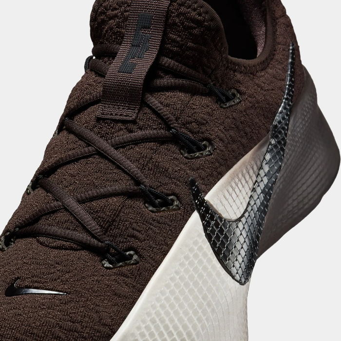 Brown athletic shoe with black and white accents on a light gray background