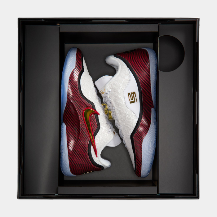 Nike LeBron XXIII "Grand Opening" sneakers in white and red with gold Swoosh and translucent sole, top view in box display.