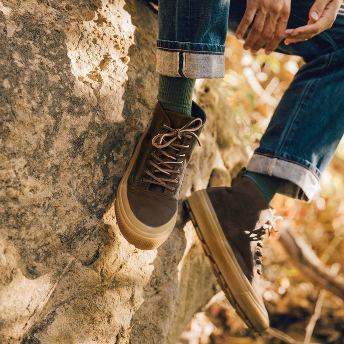 SeaVees Mammoth Boot in brown suede with rugged gum outsole and lace-up design, worn outdoors on rocky terrain.