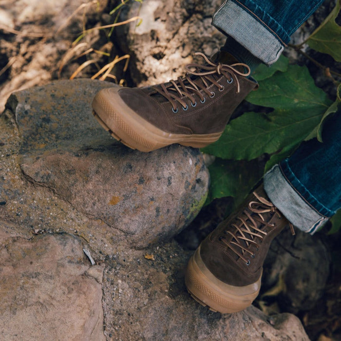SeaVees Mammoth Boot in brown suede with a durable rubber outsole and metal eyelets, worn outdoors on rocky terrain.