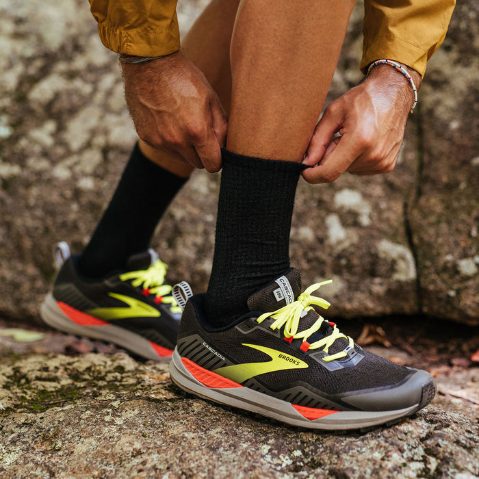 Feetures Merino 10 Ultra Light Cushion Mini Crew socks in black with moisture-wicking merino wool, worn outdoors by hiker.