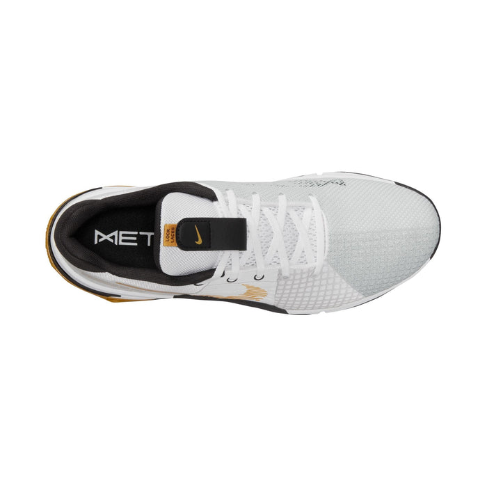 Nike Metcon 8 training shoes top view, white mesh upper with black tongue, gold accents, and lace-up design.
