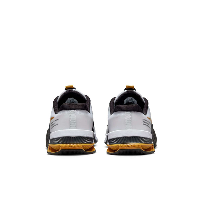 Nike Metcon 8 training shoes back view, featuring a white upper, black heel collar, and yellow outsole accents.
