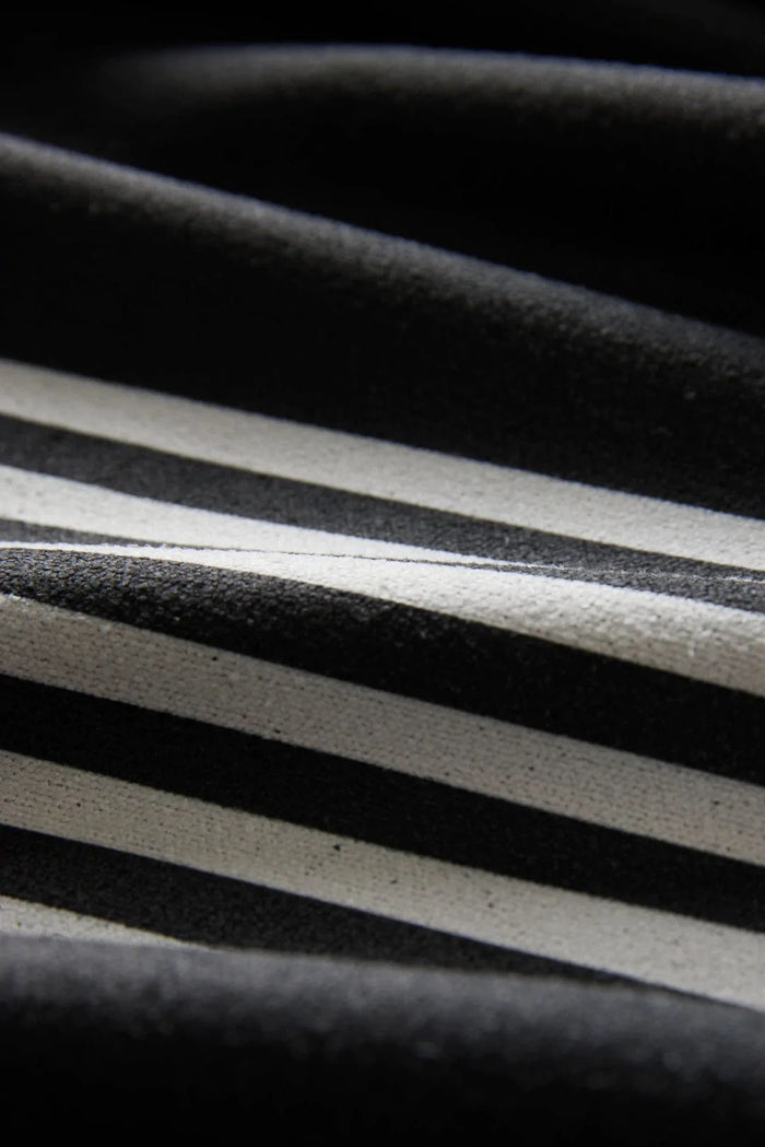 Nomadix Mini Towel in black with white stripe design, close-up view showing textured fabric details.