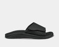 OluKai Nalu Slide sandals in black with textured strap, perforated detailing, and cushioned sole, side view.