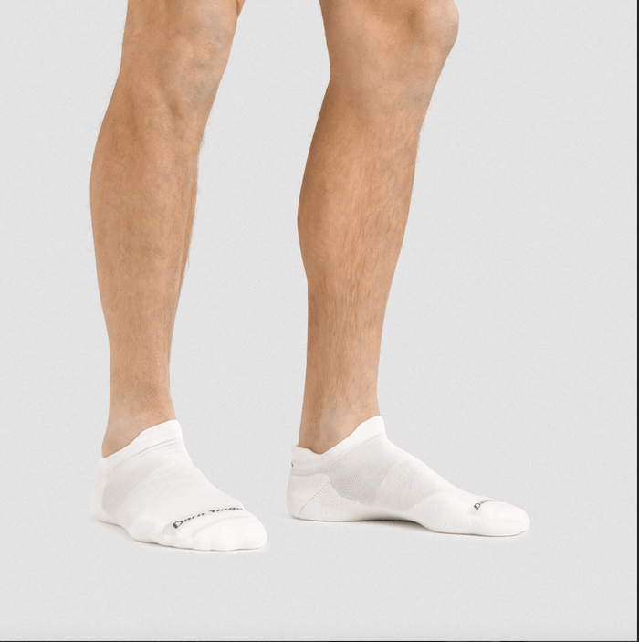 Darn Tough No Show Tab Ultra-Lightweight Running Sock in white with seamless construction, worn by person indoors.