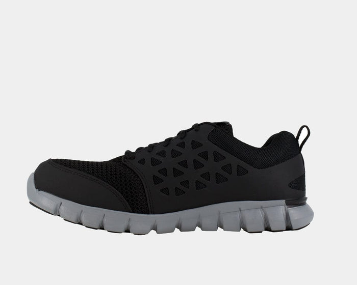 Reebok Work Sublite Cushion Work shoes in black with mesh upper, geometric overlays, and gray cushioned sole, side view.